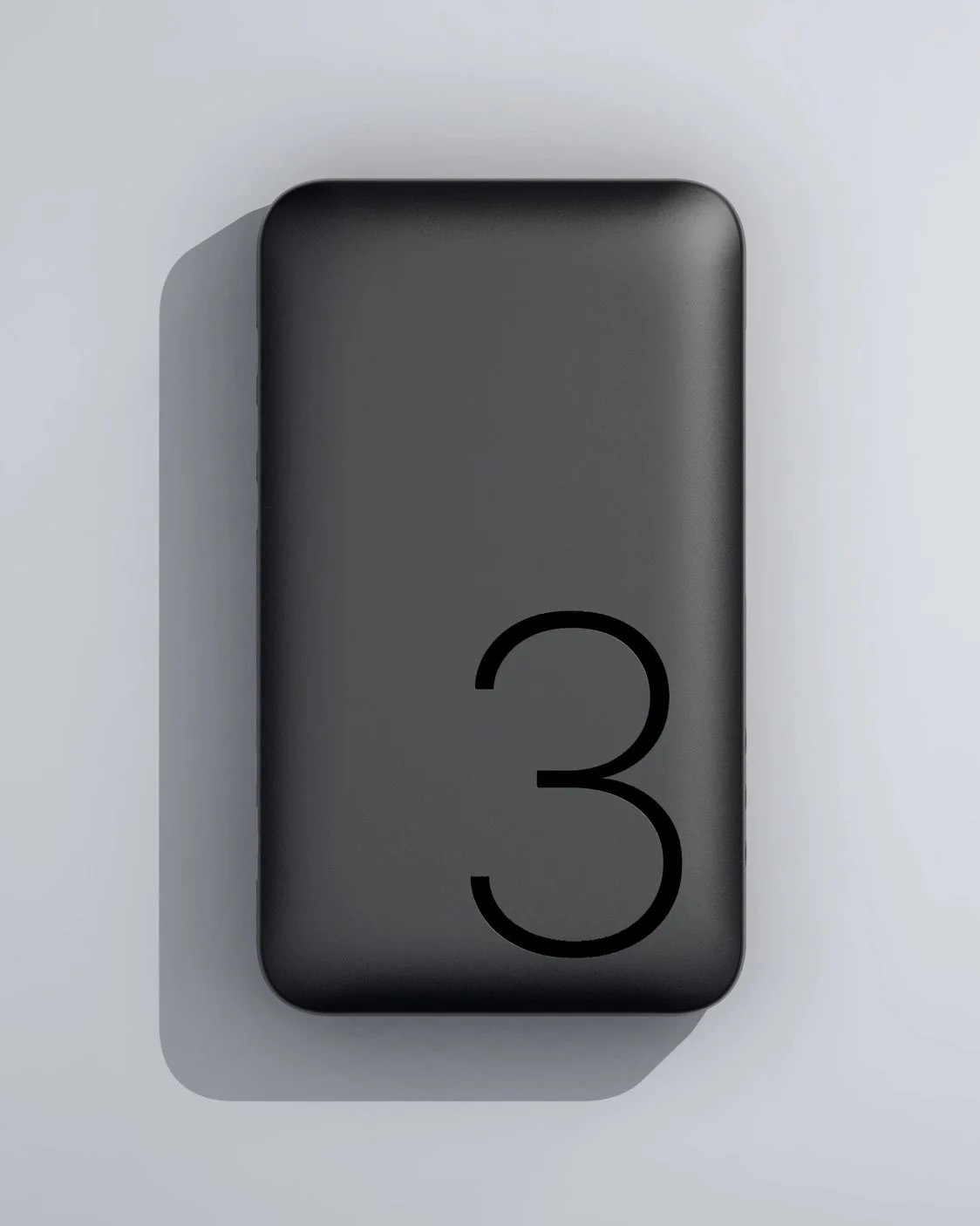 Musta suorakaiteen muotoinen esine, jossa on suuri numero 3, varjolla vaalealla taustalla.