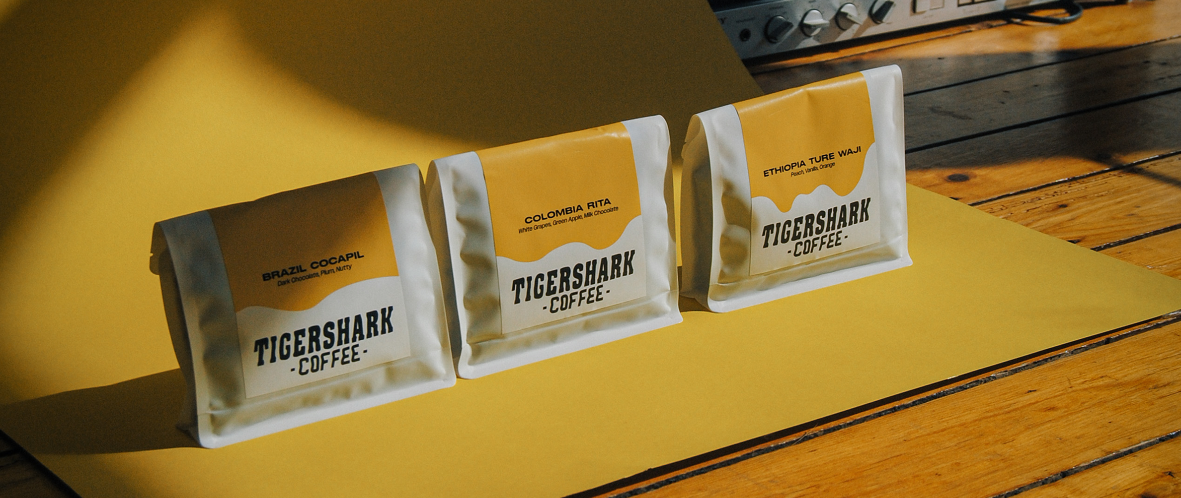 A product photo of 3 coffee bags, with white and yellow labels on a yellow background