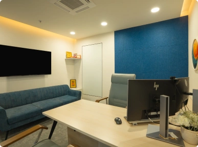Modern Ignosis AI office with sofa, desk, computer, and blue accent wall under ceiling lights.
