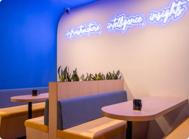Modern Ignosis AI office space with white desks, black chairs, blue dividers, and high stools near a round table.