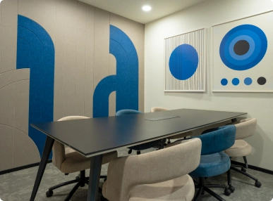 Modern meeting room with black table, beige and blue chairs, abstract blue wall art, and white walls at Ignosis AI office.