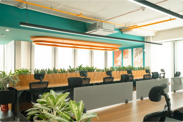 Modern conference room with wooden table, eight gray chairs, wall-mounted TV, and blue accent wall at Ignosis AI office.