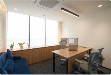 Modern seating area with three yellow chairs around a black table in a bright Manubhai & Shah LLP office space.