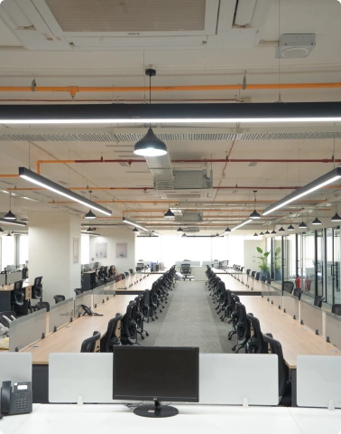 Modern Manubhai & Shah LLP office with two chairs, a desk with computer, blue walls, wooden panel, and round wall art.