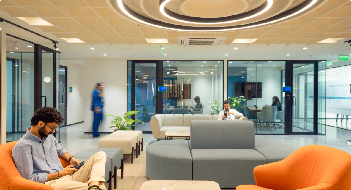 Modern office waiting area at Manubhai & Shah LLP with blue velvet chairs and sofa, a round white marble table, and Ignosis AI logo on wall.