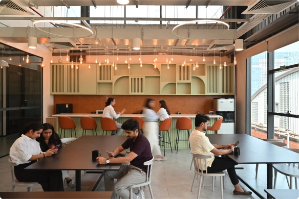 People sitting and chatting in a modern café with hanging lights and large windows at Deakin University.