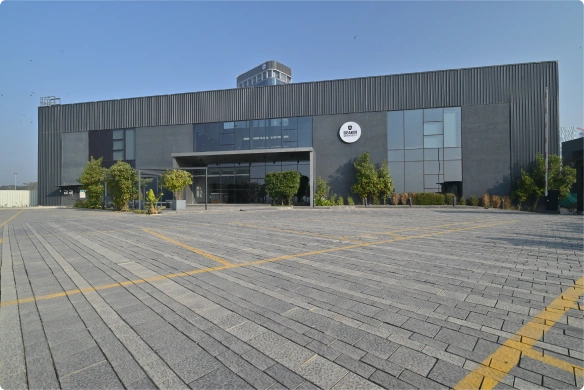 Deakin University modern dark gray industrial building with glass entrance and surrounding bushes under clear sky.