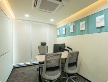Small modern office with three ergonomic chairs, a desk with monitors, and blinds covering the window at Walter P Moore.