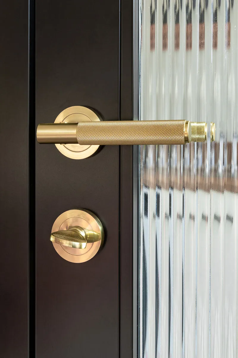 Gold Knurled handle and loc on Black aluminium door with reeded privacy glass