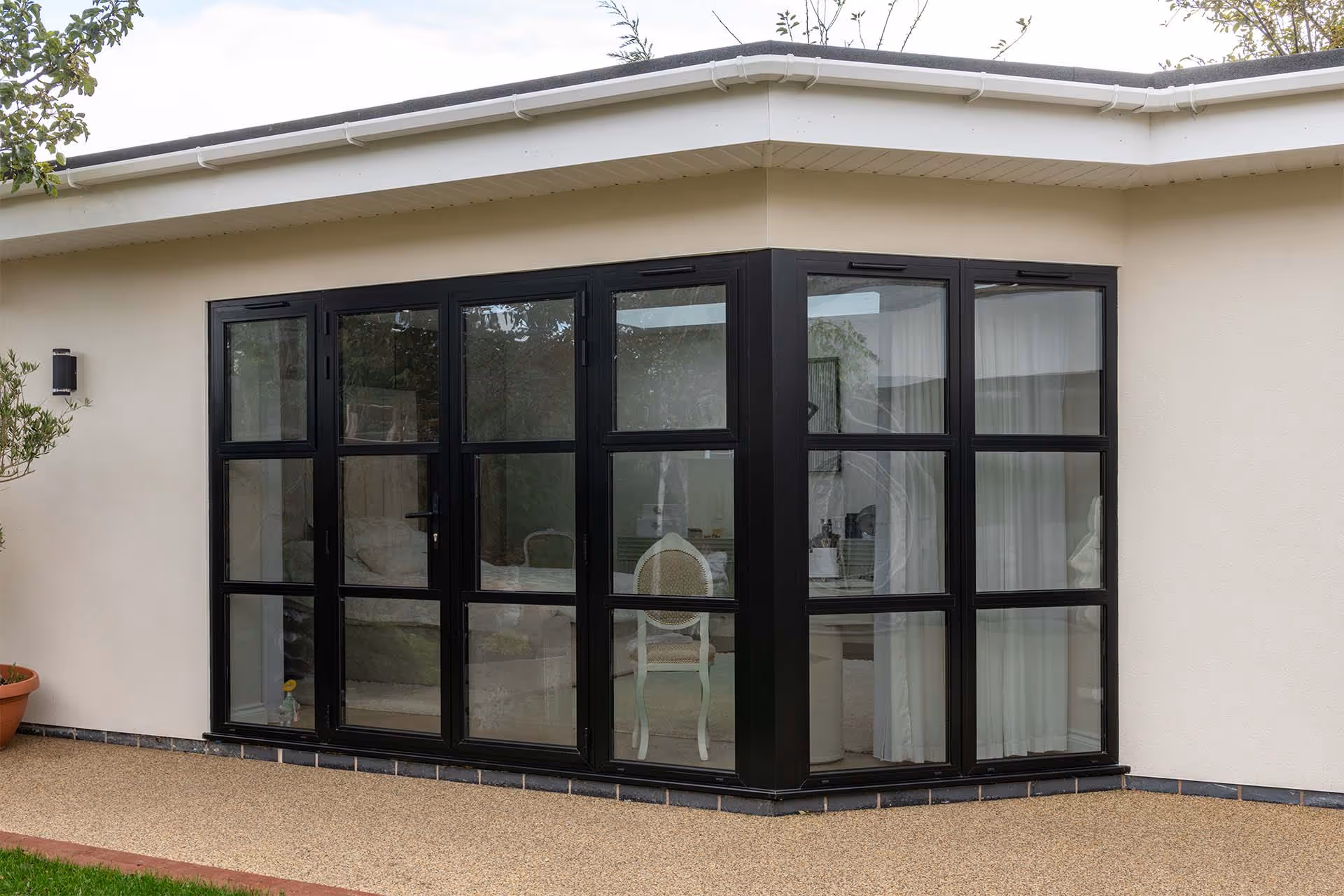 Black heritage-style aluminium doors and sidelights by Decorio fitted to a modern cream-rendered extension, creating a light-filled garden room