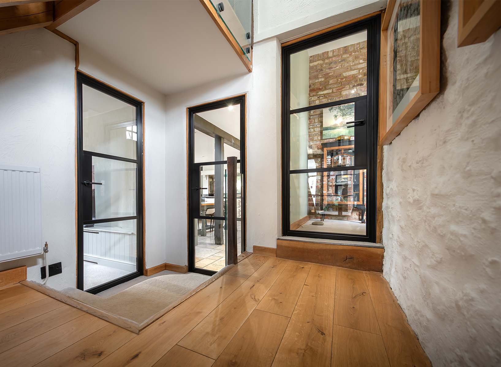 Black steel-look internal doors by Decorio installed in a characterful barn conversion, combining rustic brick and timber with contemporary glazed design