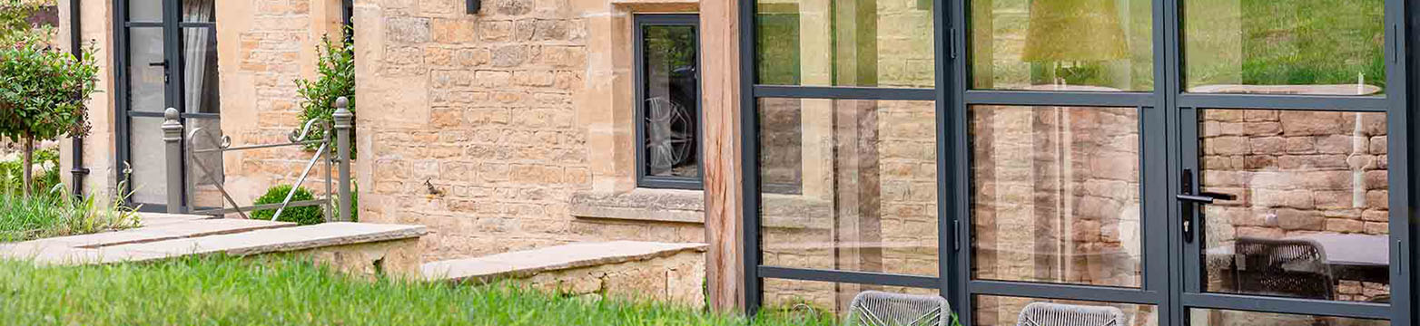 Grey Heritage Steel-look French door with sidelights on a renovated stone wall barn 
