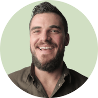 Smiling man with short dark hair, beard, and casual shirt against a light green circular background.