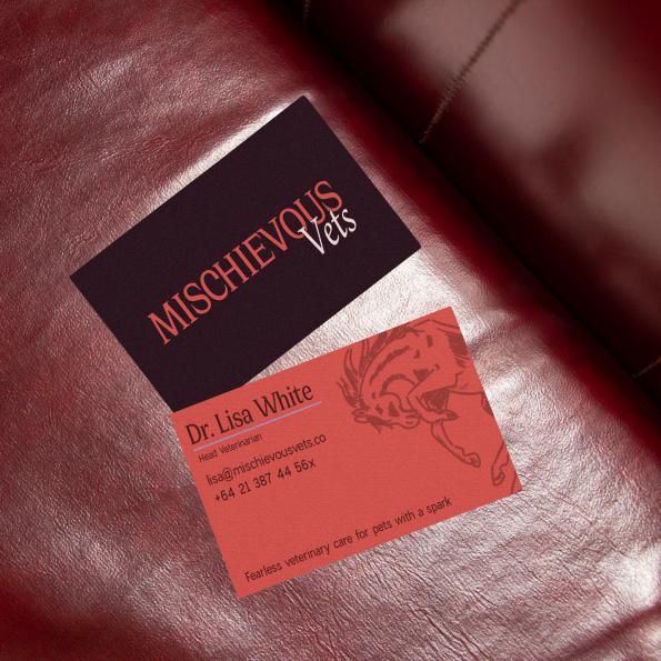 Mischievous Vets, A rebellious Veterinary Clinic: here you can see a mockup of a possible business card on a red leather couch: one side shows the logo (wild mustang + edgy wordmark) on a Deep Burgundy background, the other side is contact details