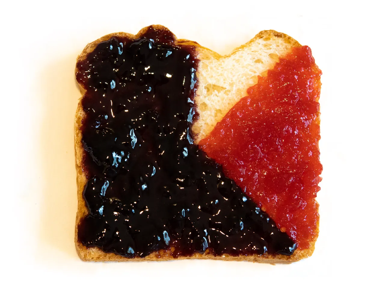 Photo of a slice of toasted bread with dark purple and red jam spread in separate sections like a pie chart.