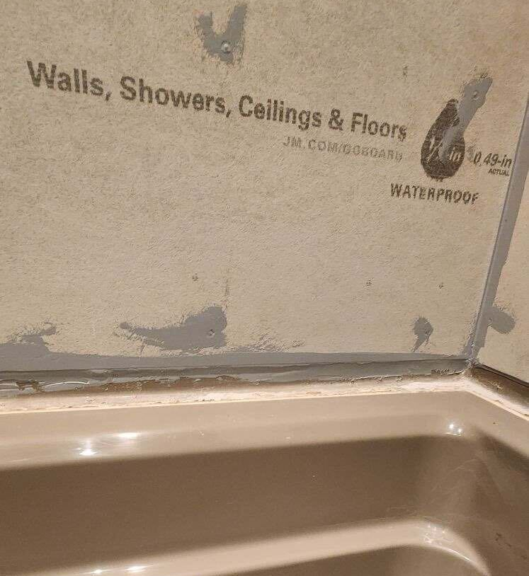 Waterproof backer board installed above the tub, replacing the failed tile backing.