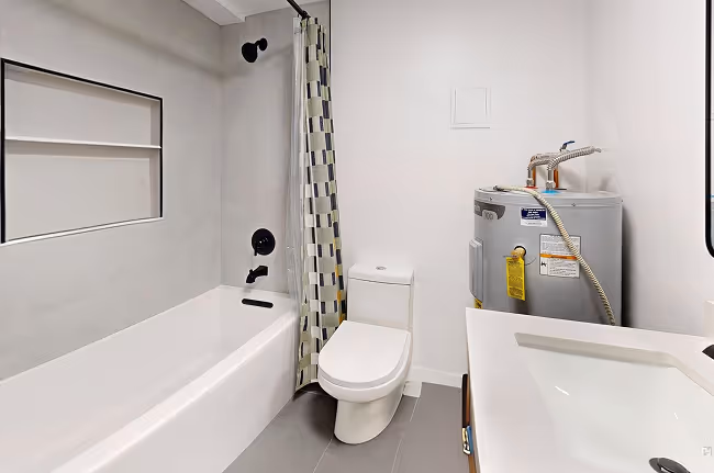 Remodeled bathroom with gray tile, sleek toilet, modern vanity, and tub-shower combo.