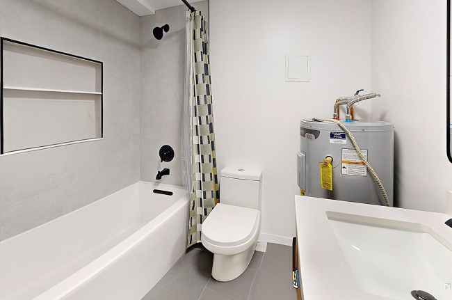 Renovated bathroom with gray tile, sleek toilet, modern vanity, and tub-shower combo.