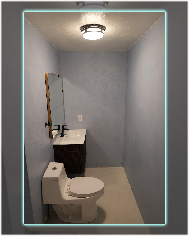 Finished microcement bathroom featuring a modern vanity, toilet, and smooth blue walls.