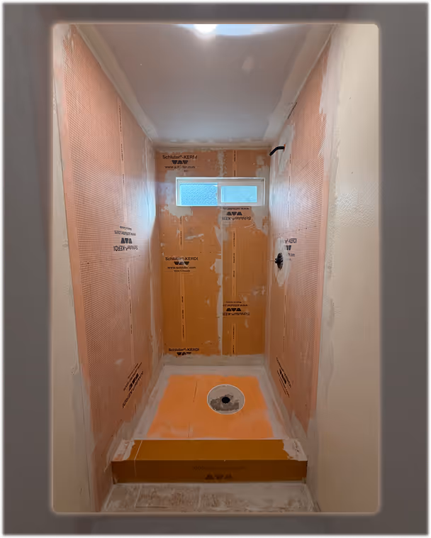 Shower renovation progress with waterproof Schluter panels installed before applying microcement.