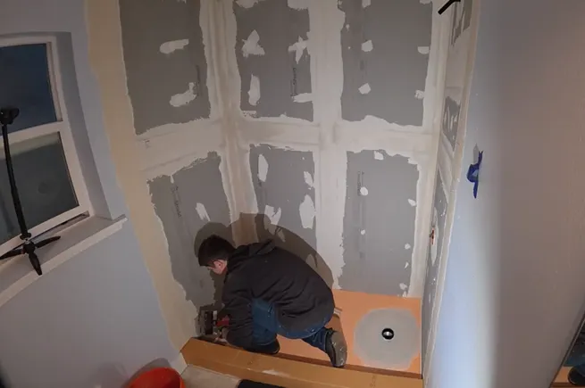Stan waterproofing the shower pan and cement board walls during tub-to-shower conversion in West Seattle.