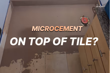 A smooth layer of microcement being applied over a tiled wall with text reading "MICROCEMENT ON TOP OF TILE?"