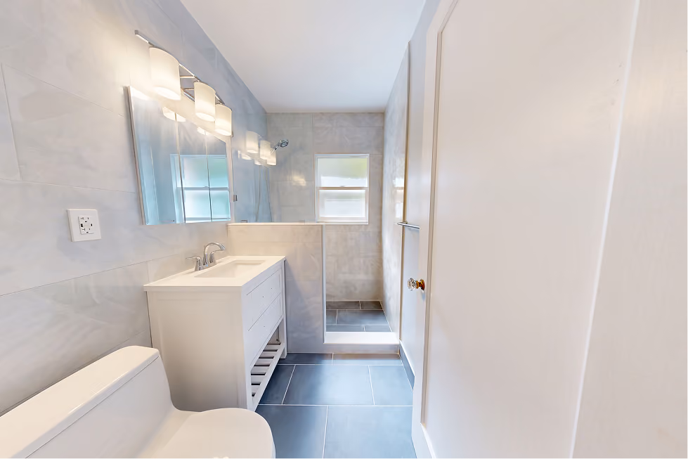 Remodeled Seattle bathroom with white vanity, walk-in shower, marble-look wall tile, and slate-blue porcelain floor