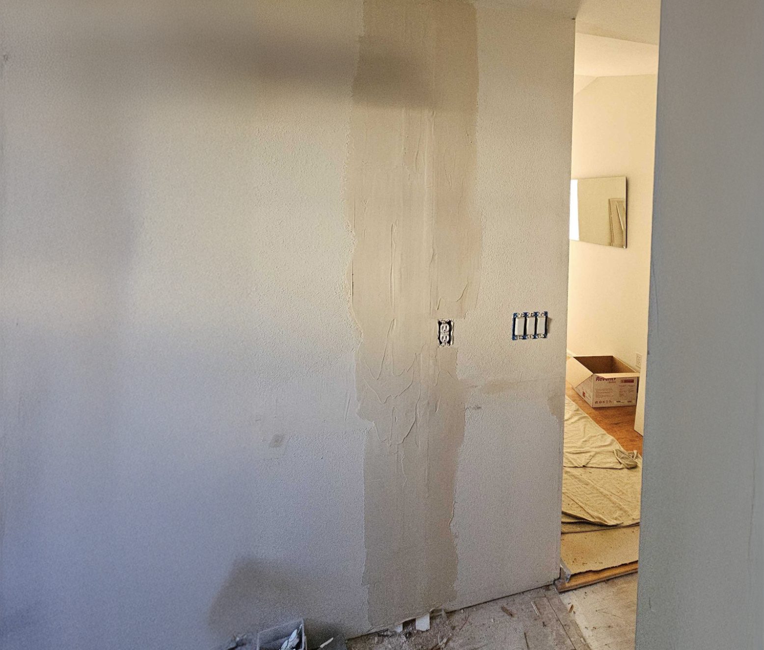 Bare wall opening where a partition was removed, looking through to the next room mid-renovation.