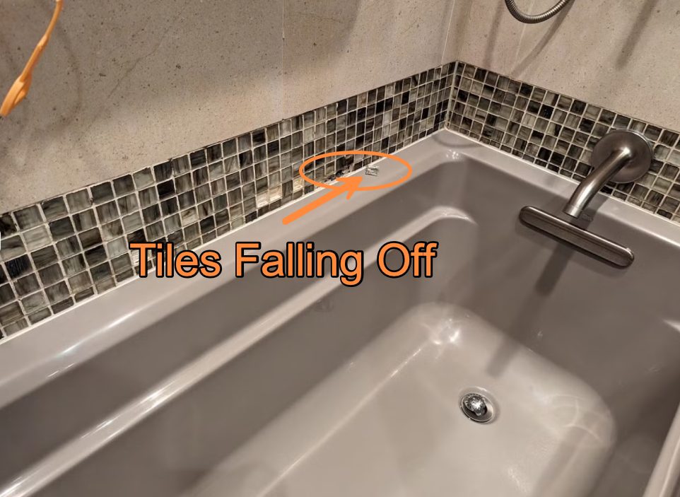 Close-up of a tub surround with an arrow marking mosaic tiles coming loose from the wall.