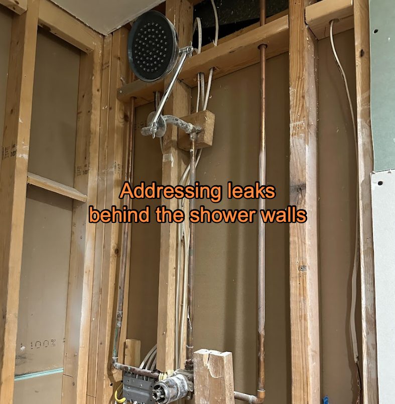 Shower wall opened to the studs, exposing the valve and supply pipes behind the tile.