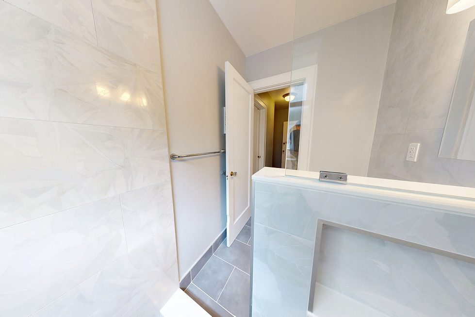 Frameless glass panel on a tiled pony wall in a renovated Capitol Hill walk-in shower
