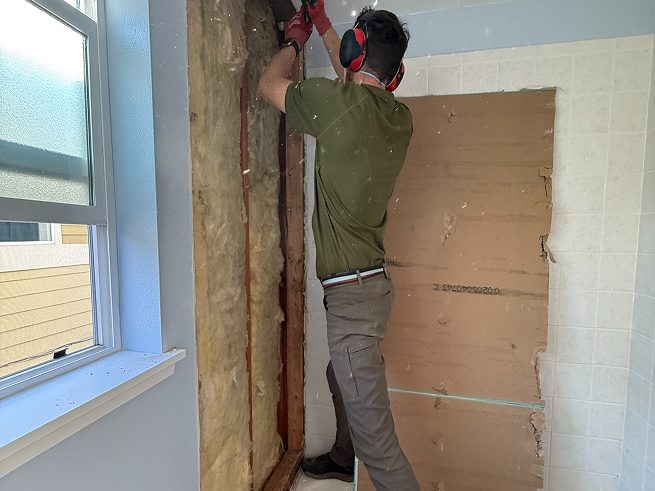 DuetRight team member demolishing tub surround down to studs during West Seattle bathroom conversion.