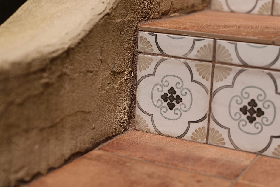 Close-up view of the staircase corner highlighting the intricate patterned riser tiles and the textured terracotta treads.