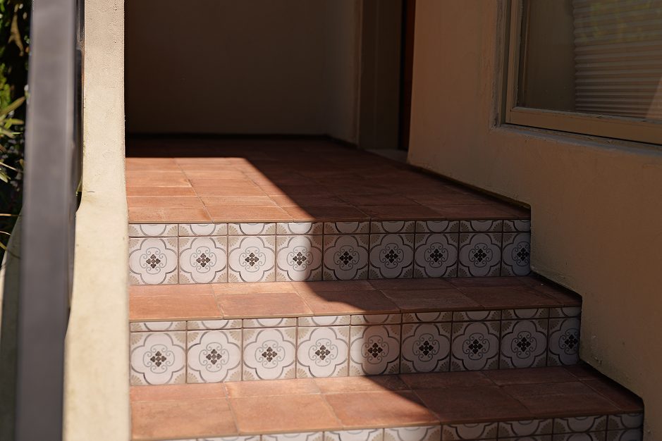 Medium shot of the finished staircase showing terracotta tile treads and decorative patterned risers leading up to a small landing.
