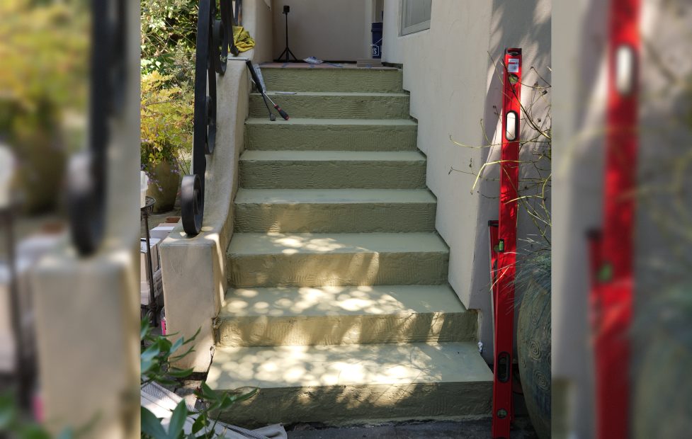 Before: worn exterior concrete steps with chipped edges and faded paint, with a level set on the treads.