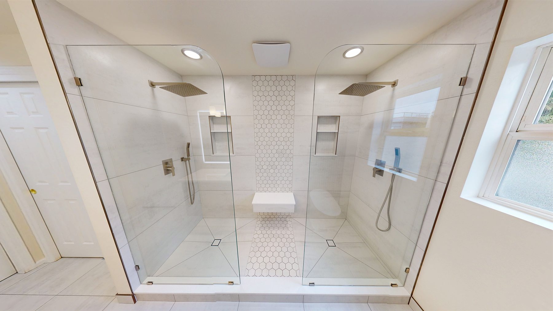 After: dual-zone walk-in shower with frameless glass, white tile, and twin skylights.