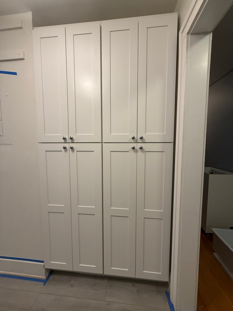 Full-height white shaker pantry cabinets installed on the entry wall