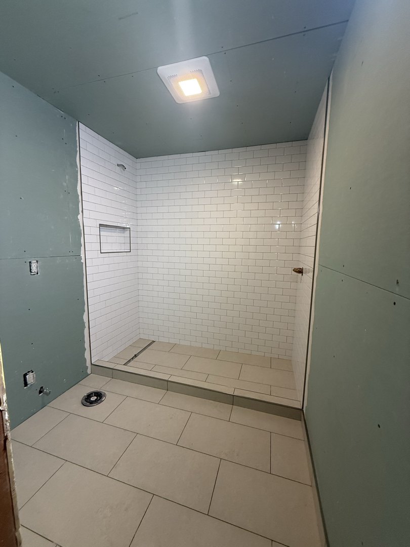 A Seattle shower tiled in white subway laid in a horizontal running bond, with a recessed niche and large-format floor tile