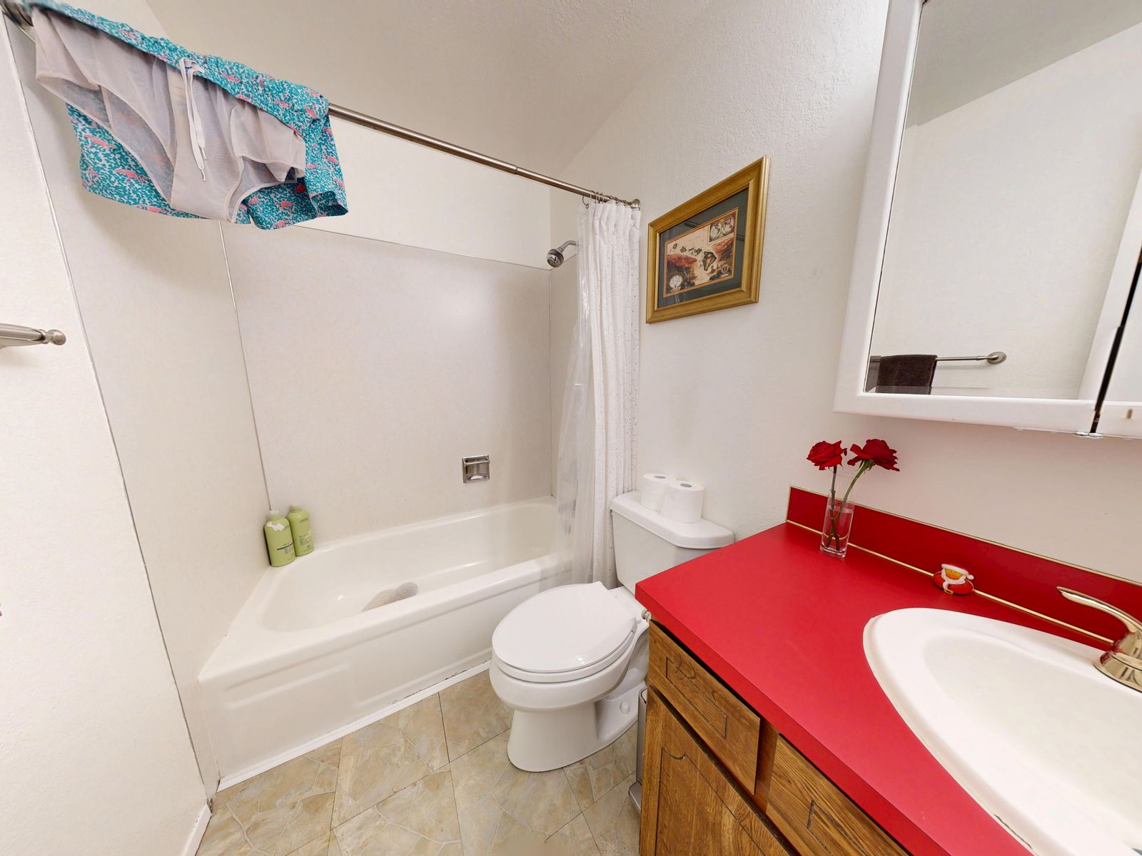 Guest bathroom before renovation with a red laminate countertop, brass faucet and fiberglass tub surround
