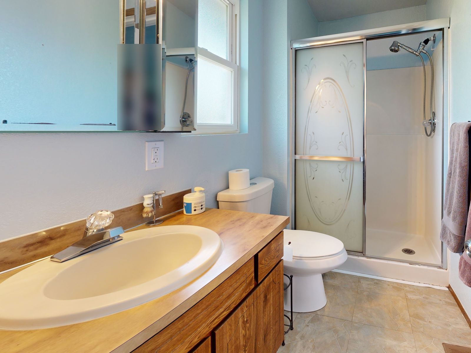 Master bathroom before renovation with a framed glass shower door, almond sink and oak vanity
