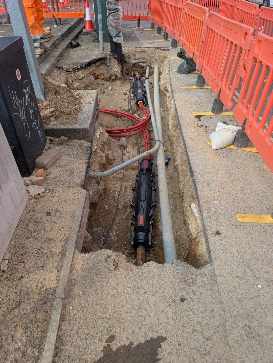 Streetworks excavation in a busy footway with cable joints and ducts