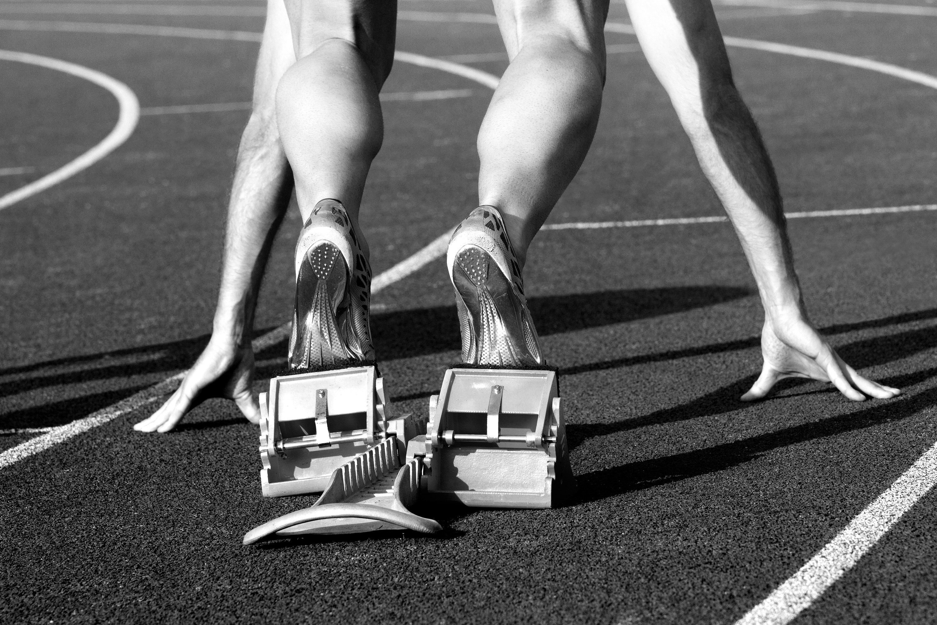 The picture shows a sprinter in the starting blocks, ready to race