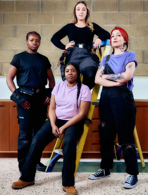 Four TaskHer tradeswomen posing together with a stepladder in a workshop