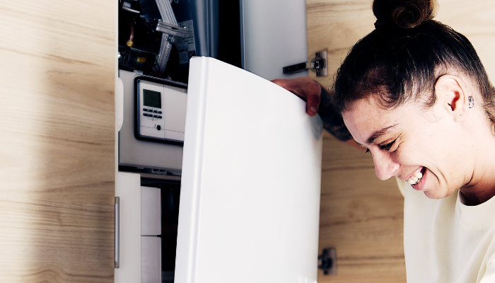 Female Gas Safe engineer taking front off combi boiler