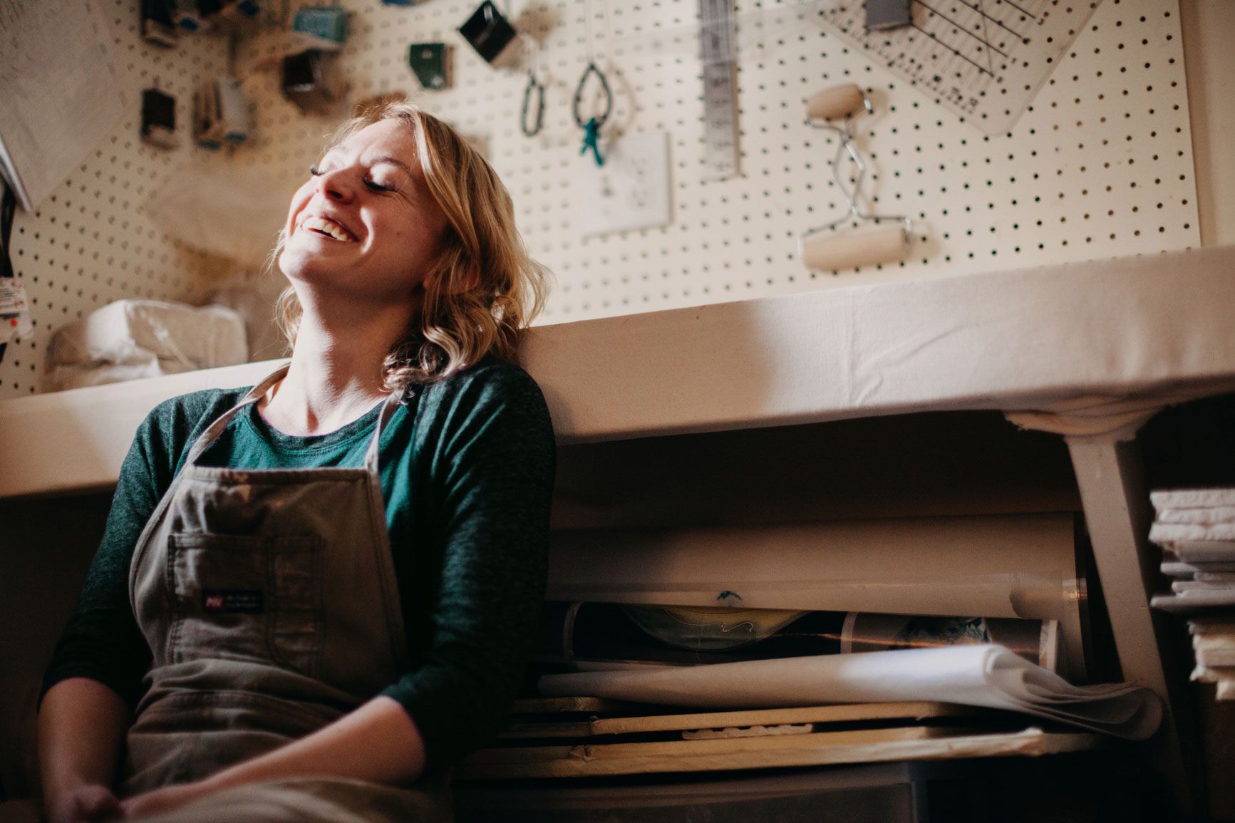 Female handywoman laughing in her workshop surrounded by tools, TaskHer
