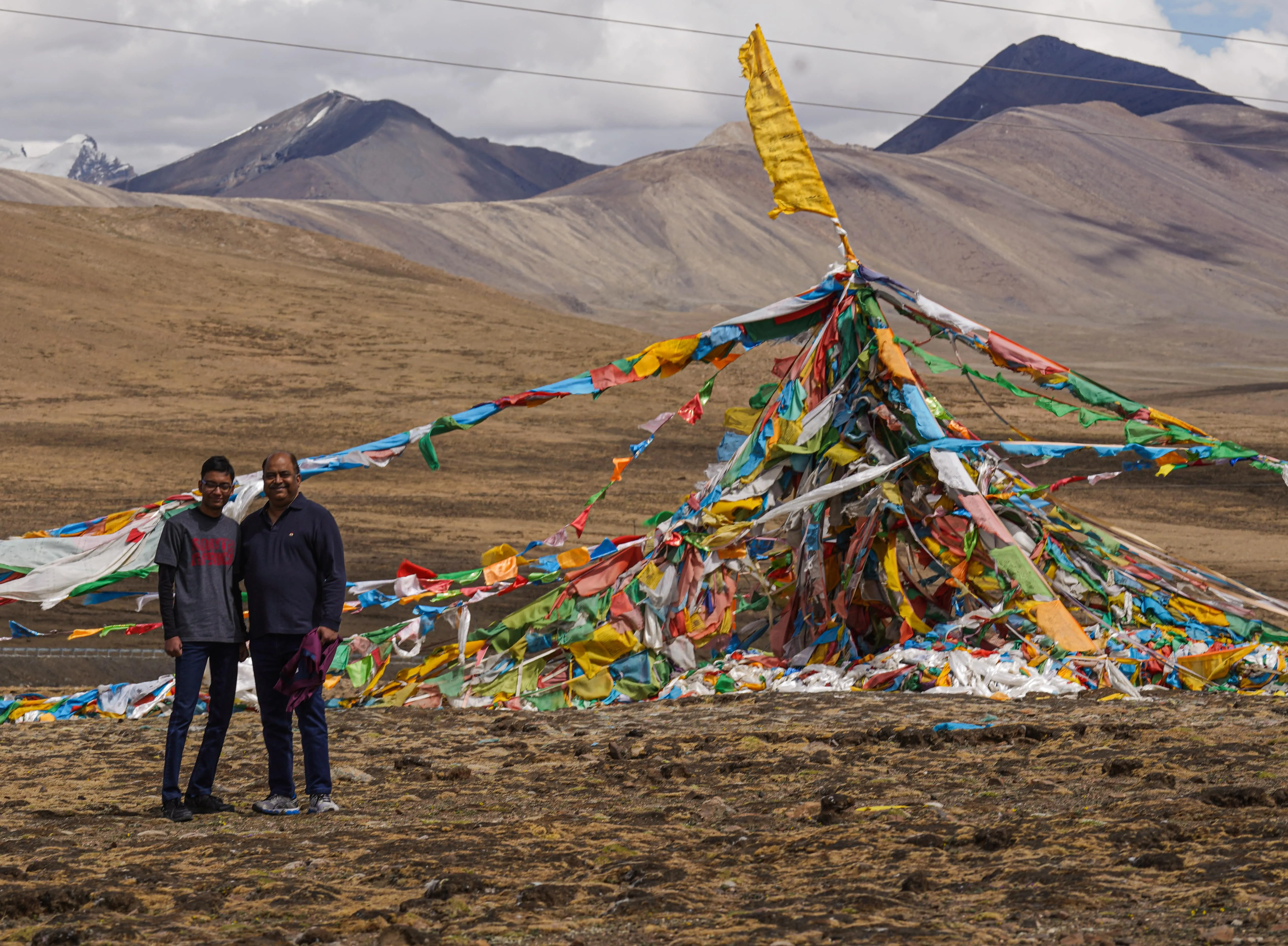 The selected region shows a large, pyramid-like mound of colorful Tibetan prayer flags (Lungta) standing prominently against a mountainous plateau backdrop.