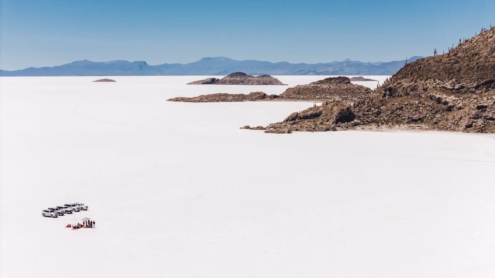 Aerial view of travellers and 4WD vehicles beside Isla Incahuasi on Bolivia's Salar de Uyuni.