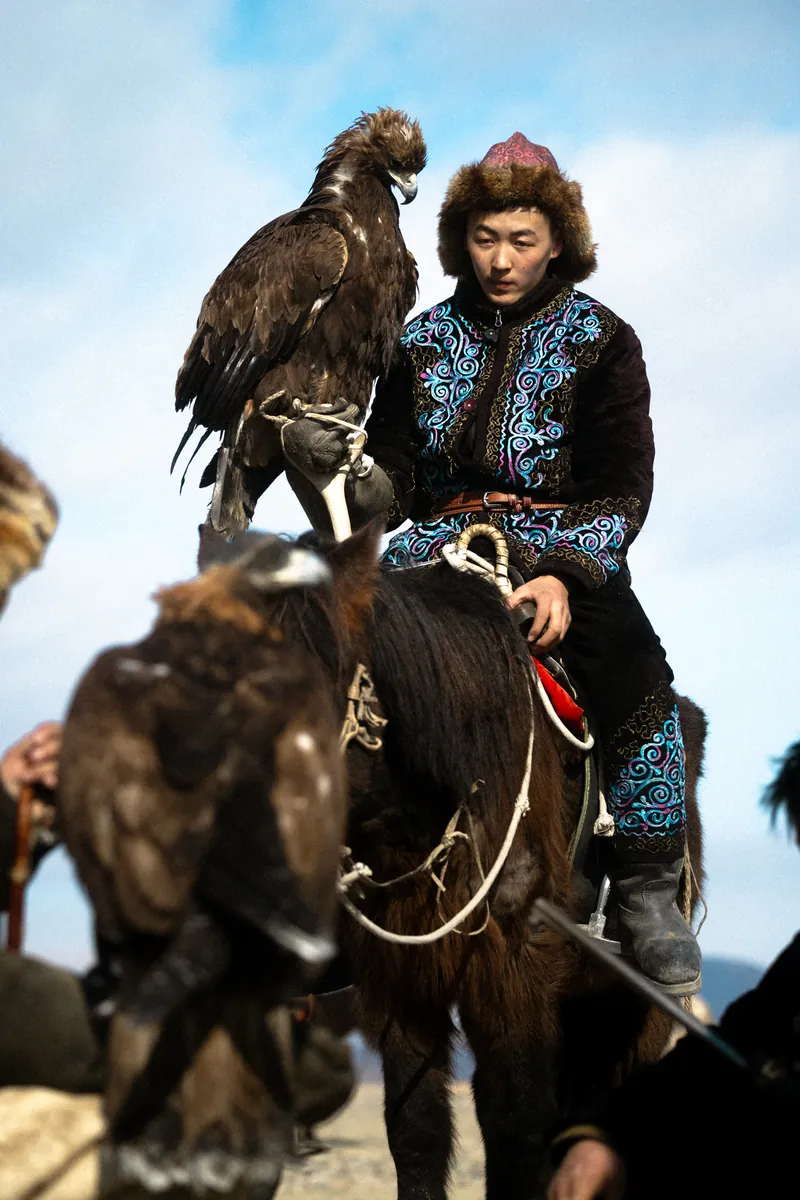 A Kazakh eagle hunter on horseback with a golden eagle, Ulgii, Mongolia
