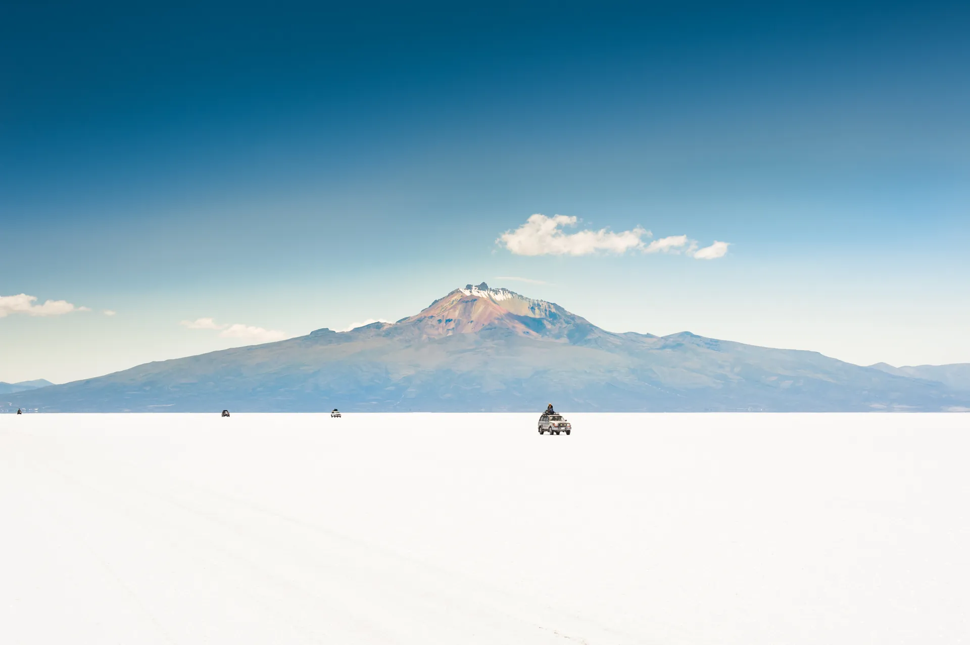 A 4x4 crossing the Salar de Uyuni below the Tunupa volcano, Bolivia