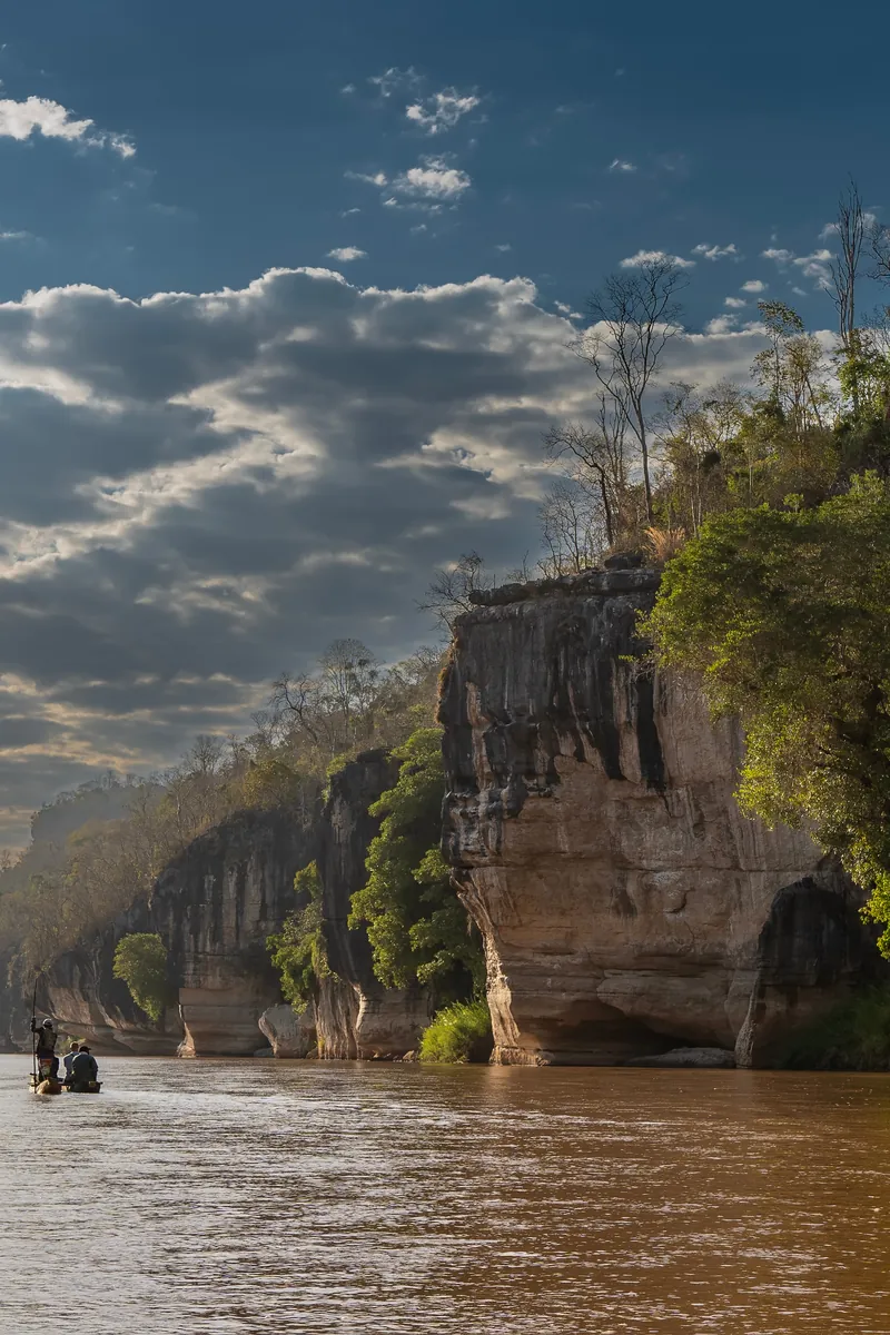 A pirogue on a river below the cliffs of the Makay canyons, Madagascar